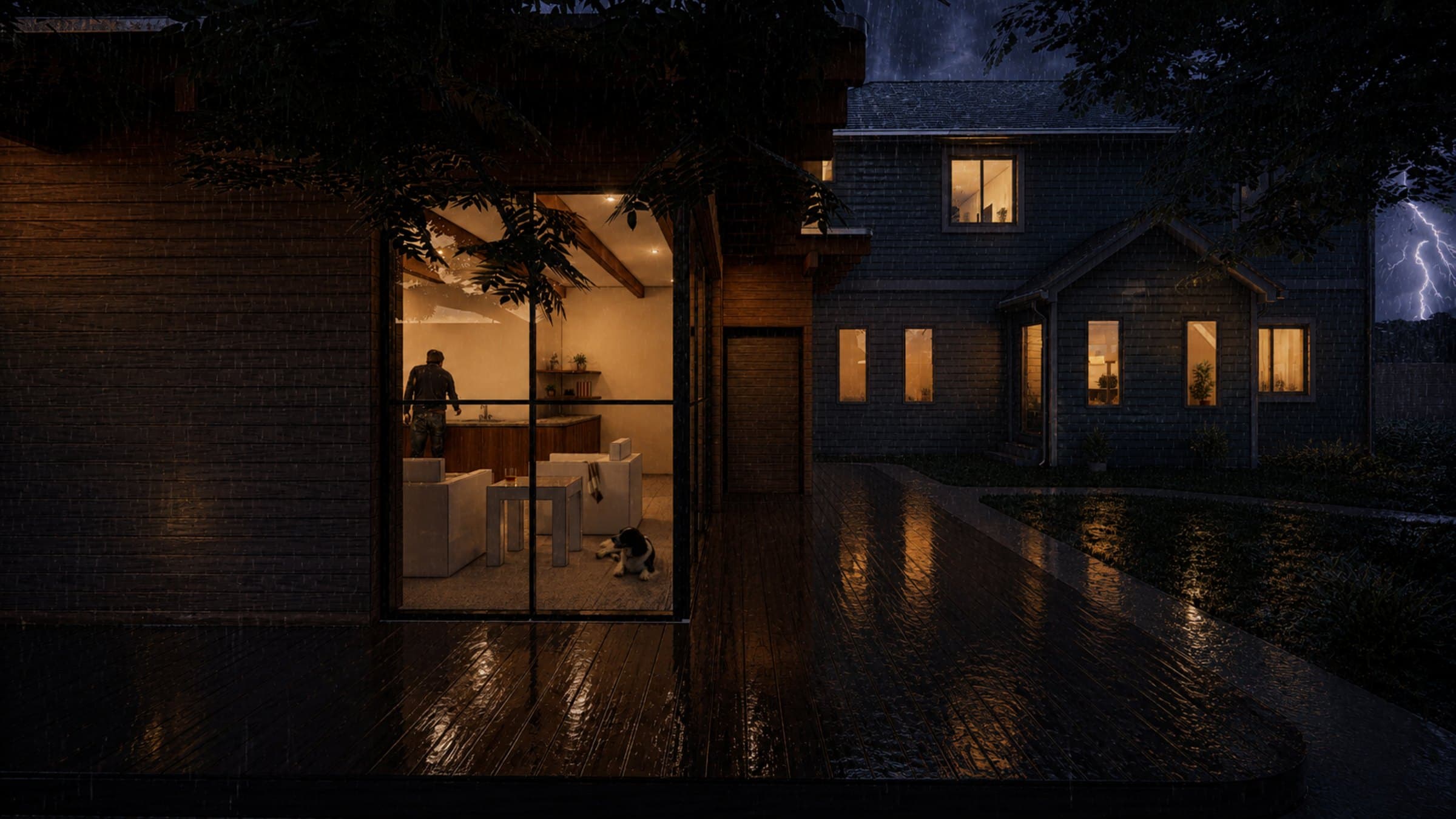 A Member backyard home glowing warm through a storm at night — lightning over the main house, every window lit while the grid is down.